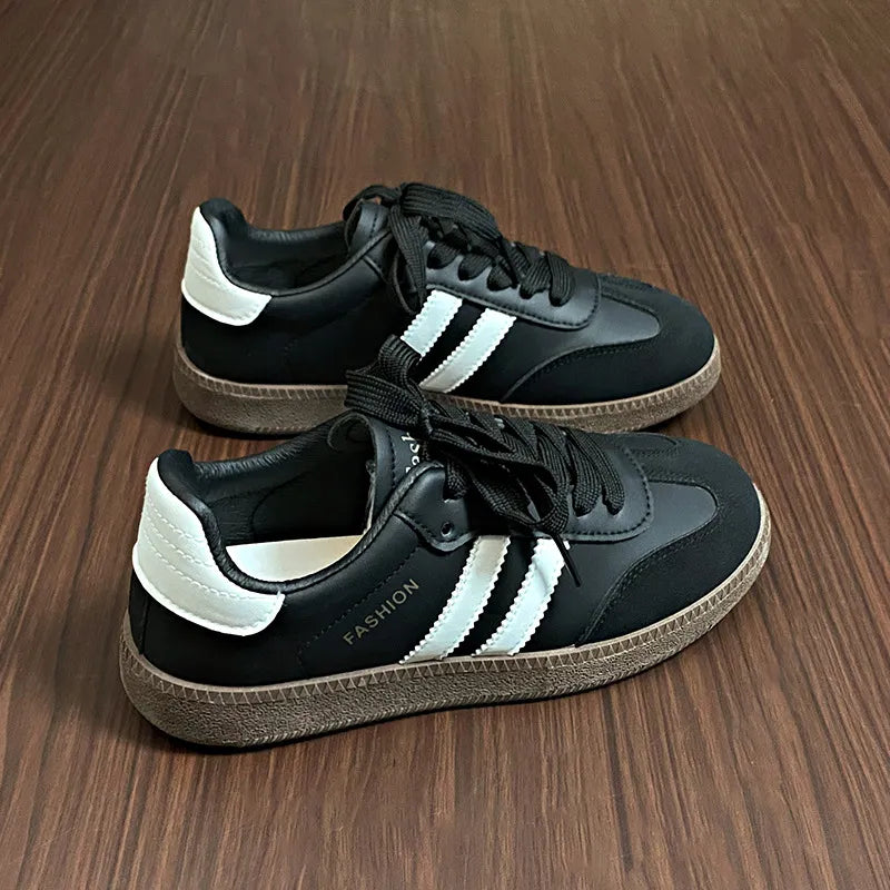 Black lace-up sneakers with white side stripes and thick textured sole