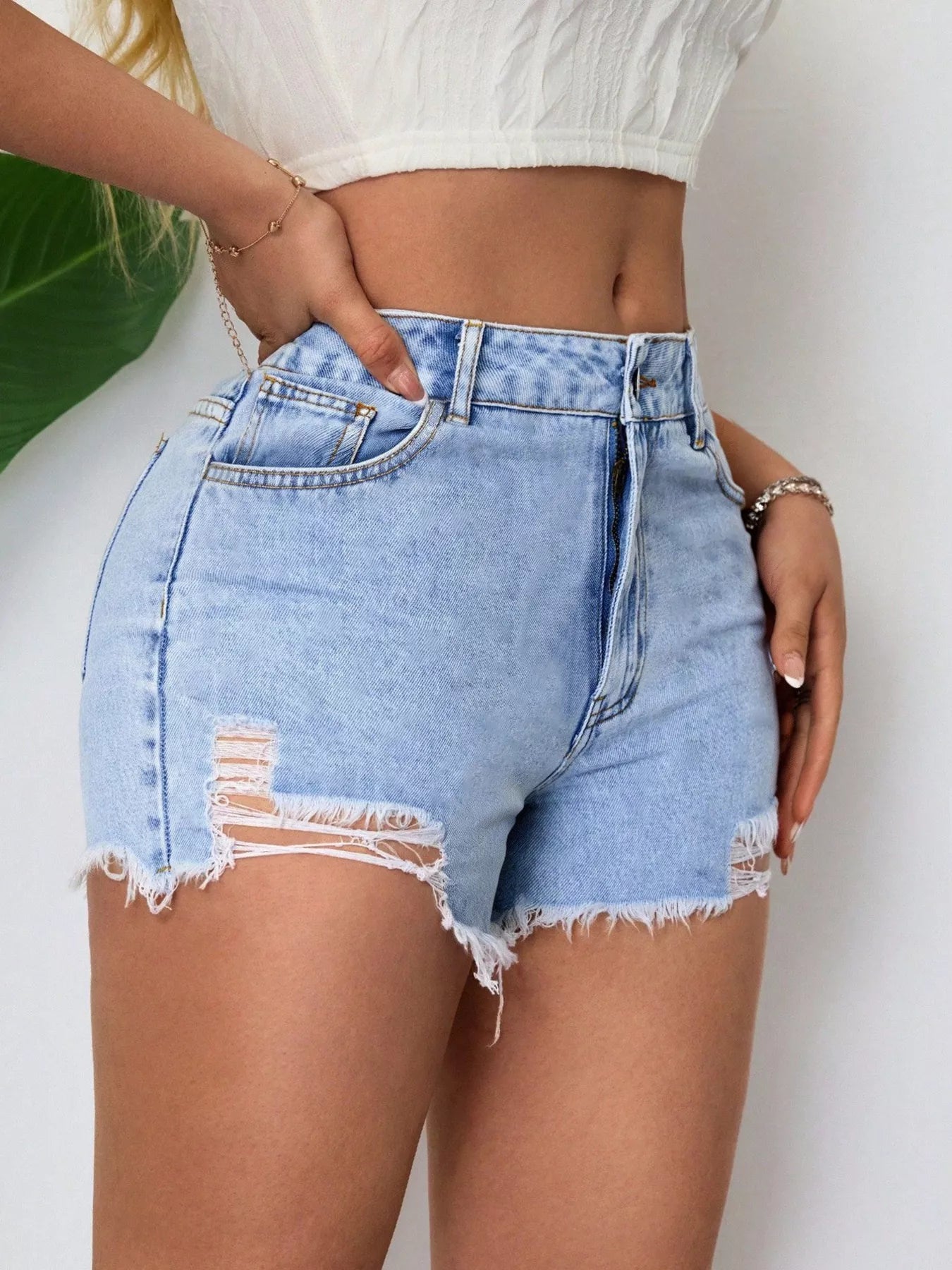 Light blue distressed denim shorts with frayed raw hem and patch pocket distress