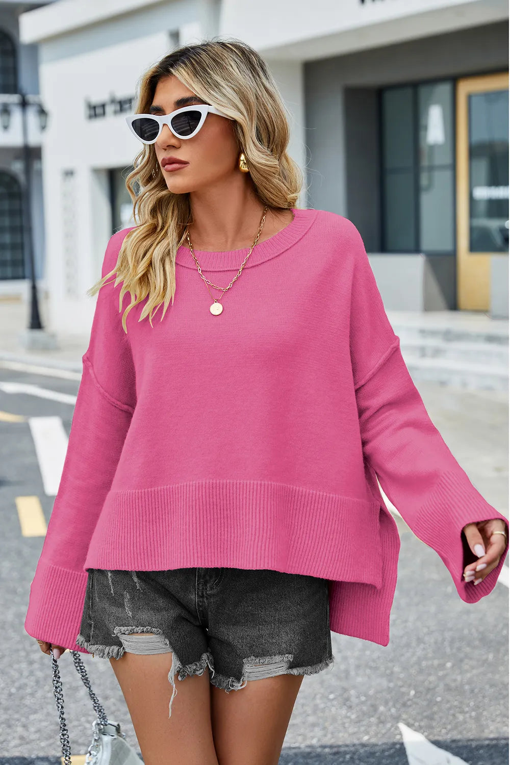 Hot pink high-low slit sweater with round neck and long sleeves, ribbed hem.