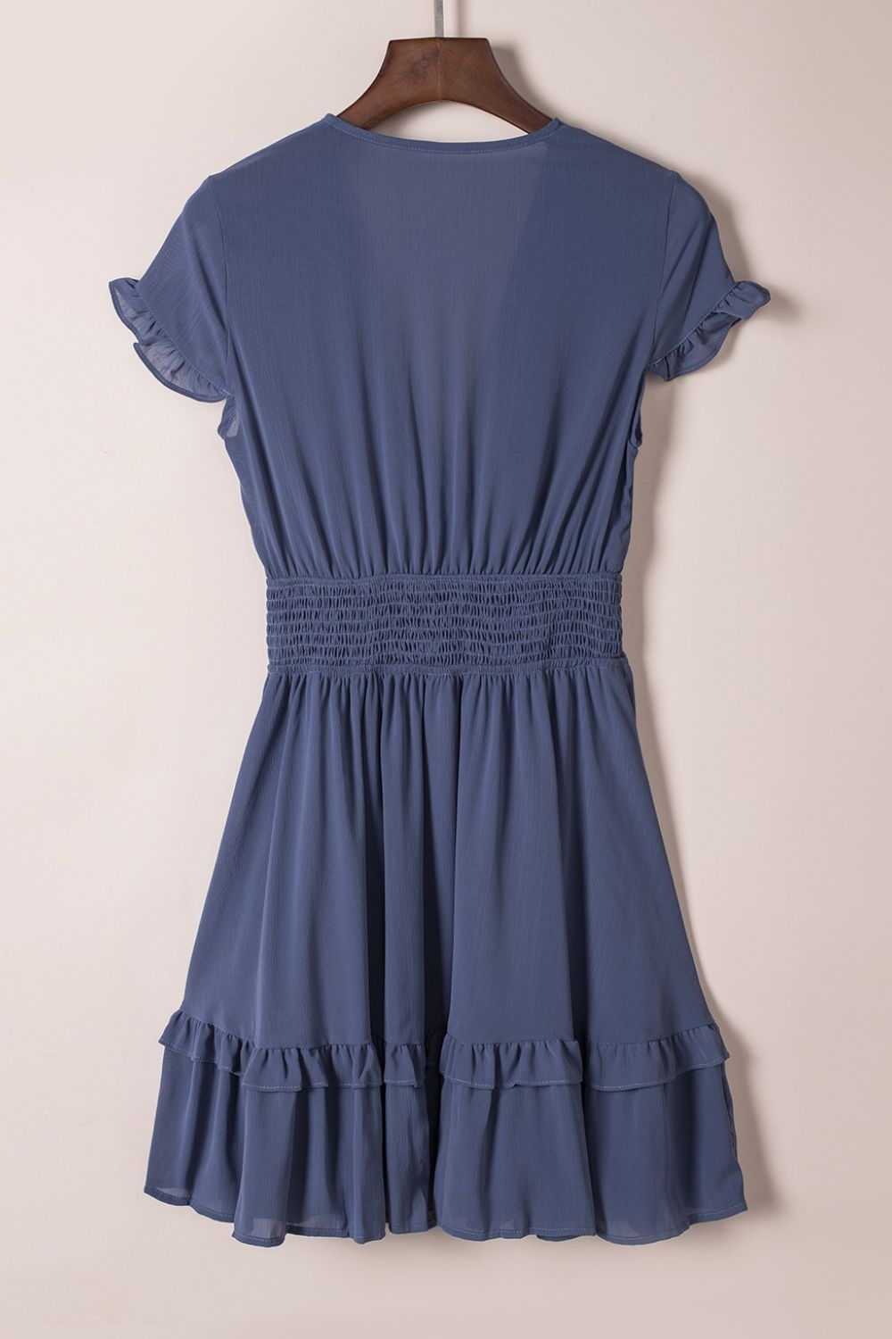 Dusty blue ruffle mini dress on hanger, back view with tiered skirt and smocked waist
