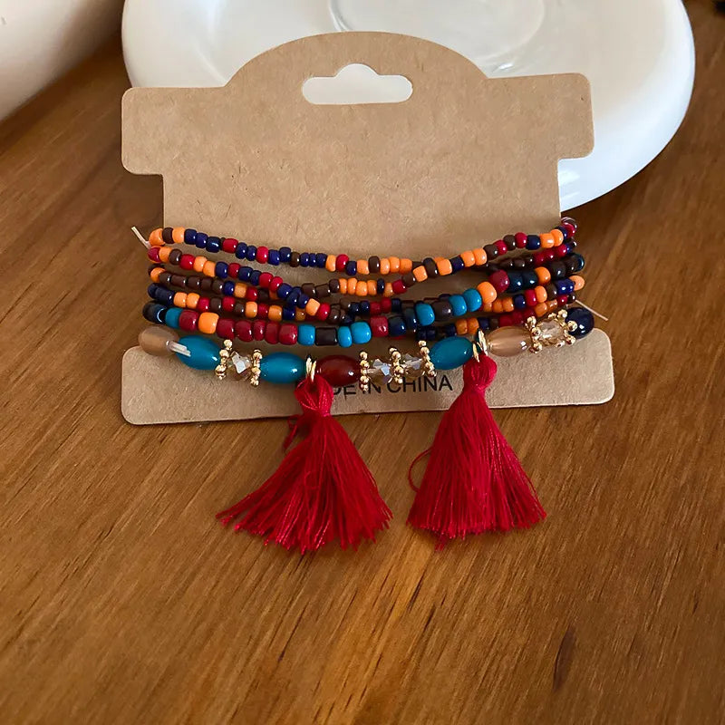 Multicolor beaded tassel bracelet with red tassels and gold-tone charm accents