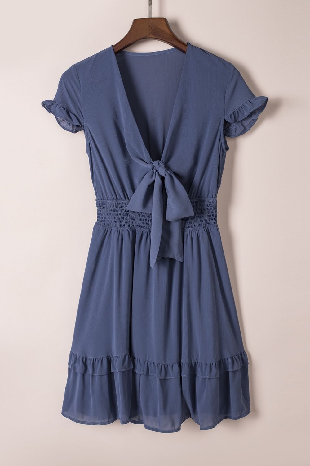 Dusty blue sleeveless? No—Dusty blue bow-tie V-neck ruffle mini dress on hanger, front view