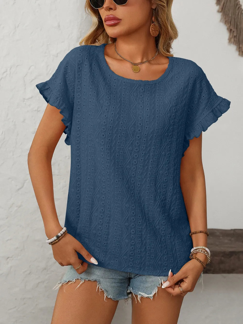 Blue eyelet round-neck short sleeve top with layered sleeves and textured eyelets.
