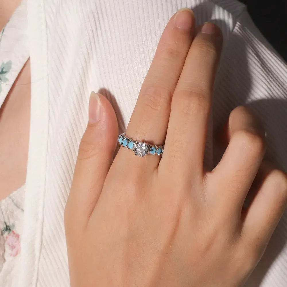 Turquoise inlay band ring with silver-tone prong setting on finger