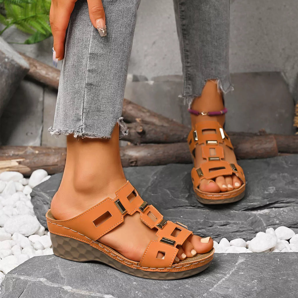 Orange open-toe wedge sandal with layered square cutout straps and buckle closures.