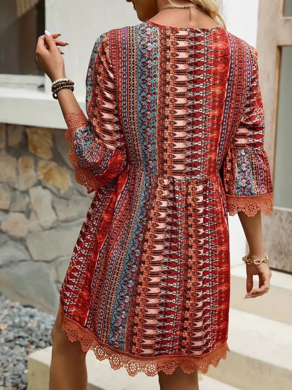 Back view of rust striped V-neck dress with lace hem and corset-style panel