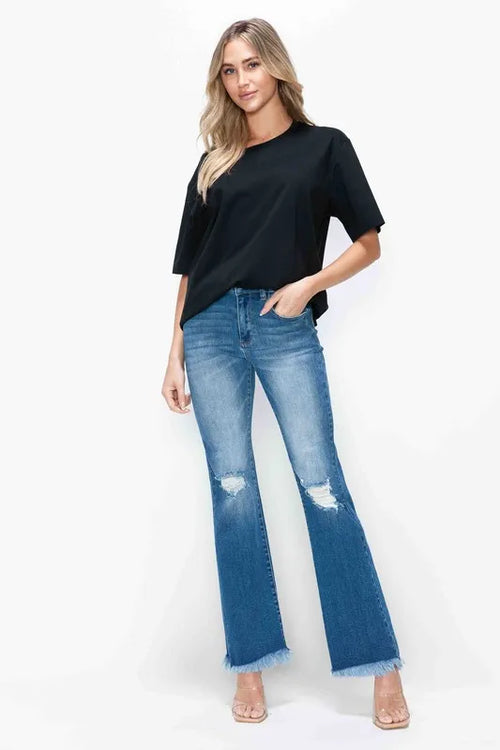Women’s high rise bootcut jeans in medium blue with raw hem and distressed patches