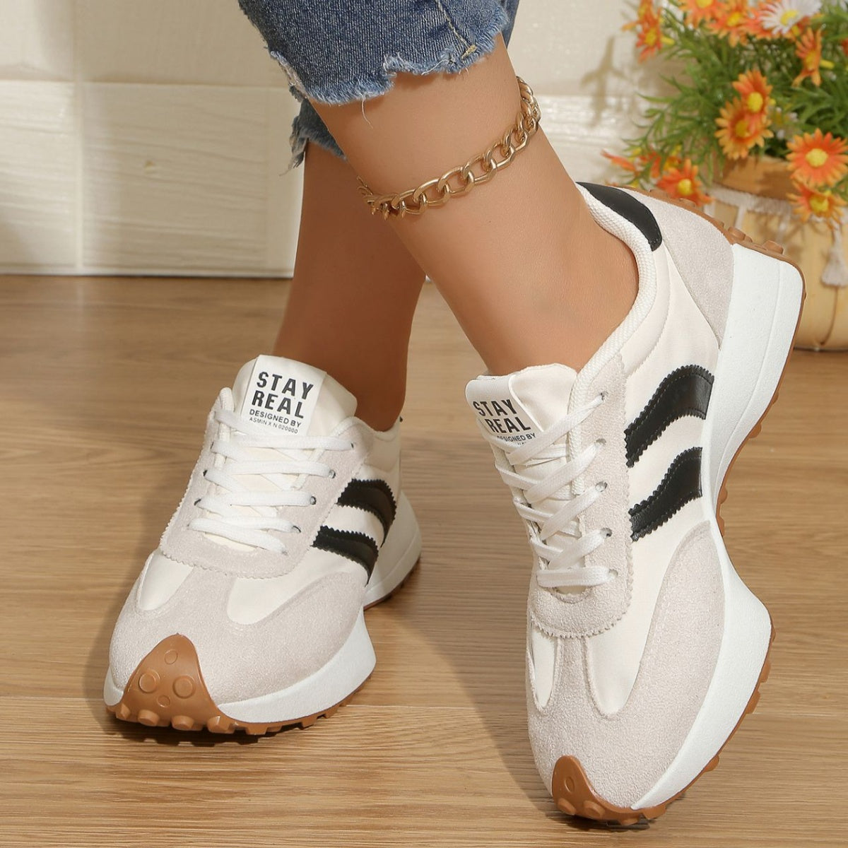 White lace-up sneakers with black stripe accents, round toe, light brown traction outsole