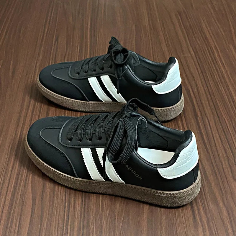 Black lace-up sneakers with white side stripes and round toe