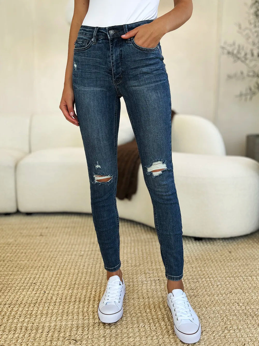 Dark blue mid-waist slim jeans with ripped knee distress and frayed hems