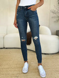 Dark blue mid-waist slim jeans with ripped knee distress and frayed hems