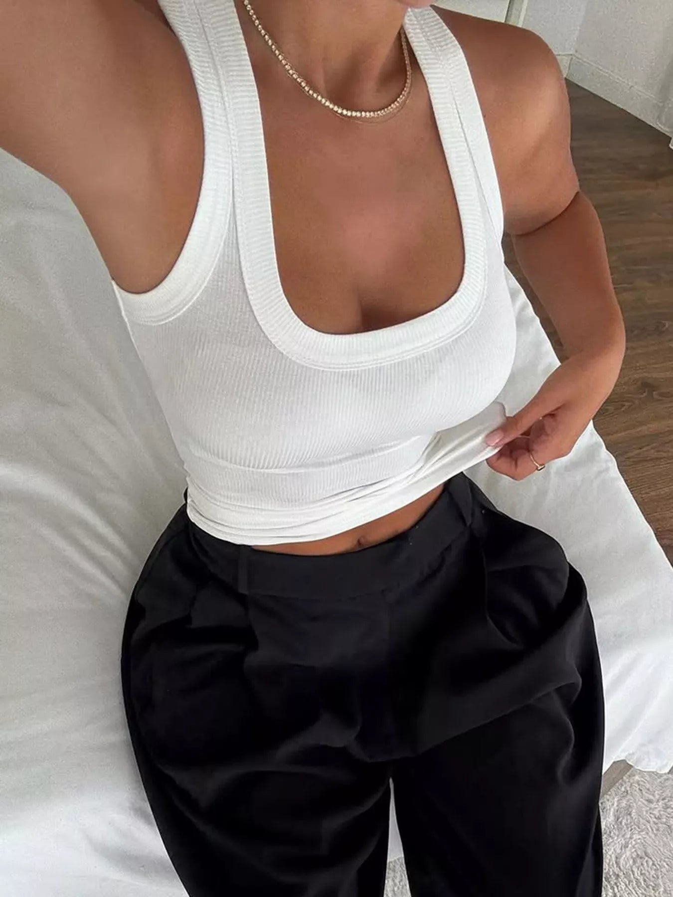 White ribbed knit slim-fit tank with scoop neckline, worn with black bottoms