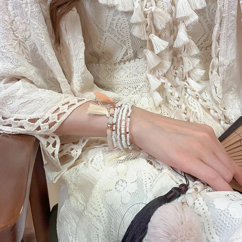 Tassel bead bracelet with dark thread, gold beads, and white tassels
