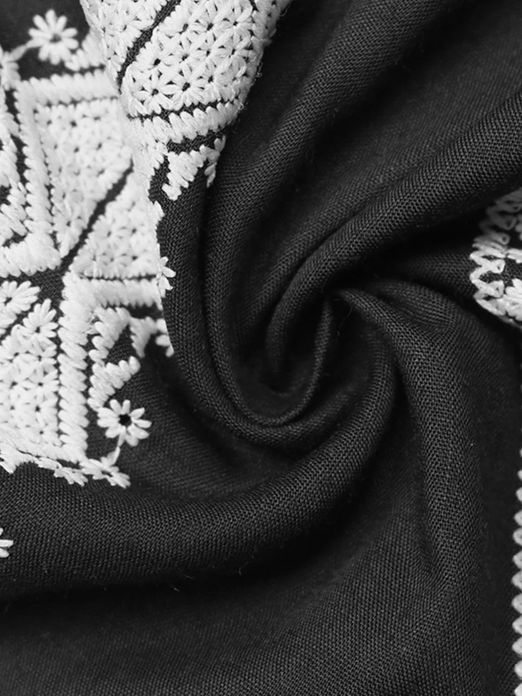 Black fabric with white embroidered geometric motifs