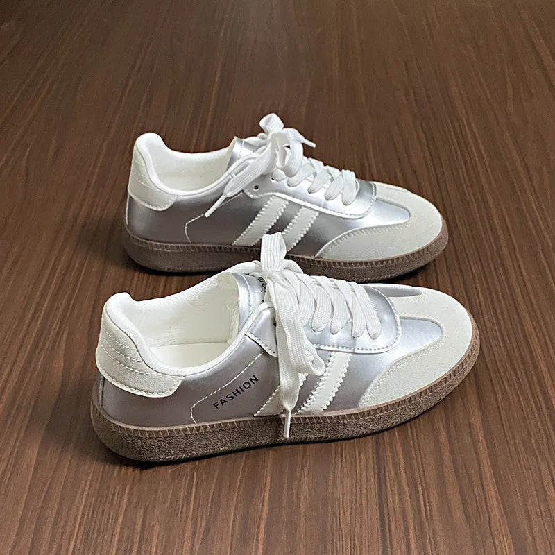 White lace-up sneakers with side stripes and padded collar, rounded toe