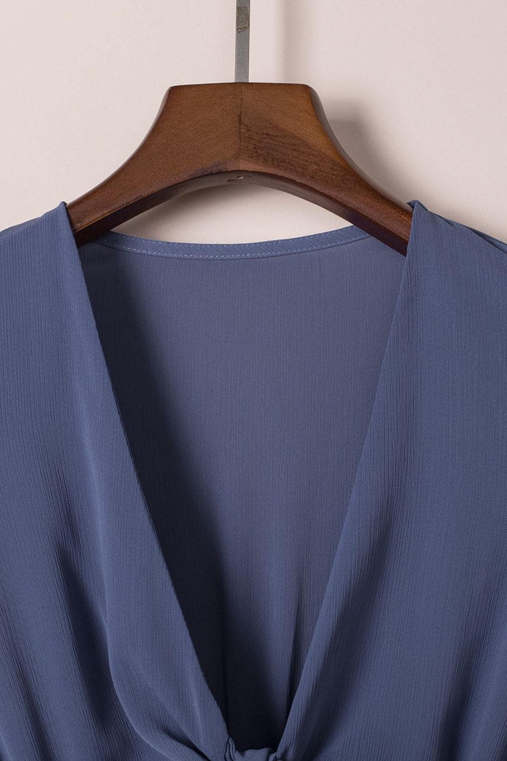 Dusty blue V-neck ruffle mini dress close-up on hanger, open neckline and soft drape