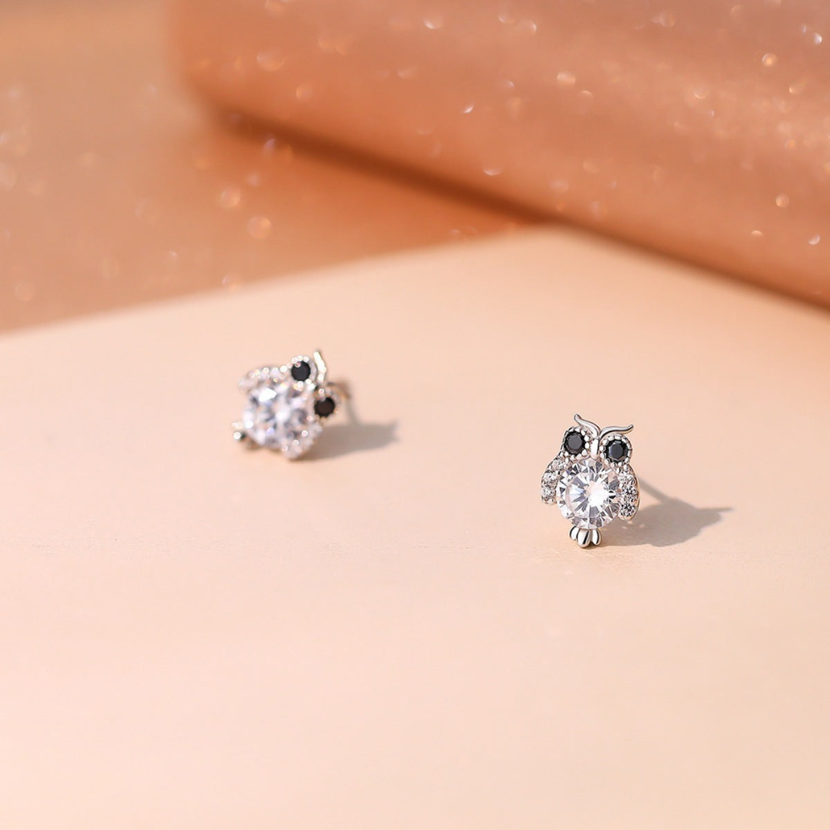 Owl stud earrings, crystal-clear owl face with black eye accents, angled close-up
