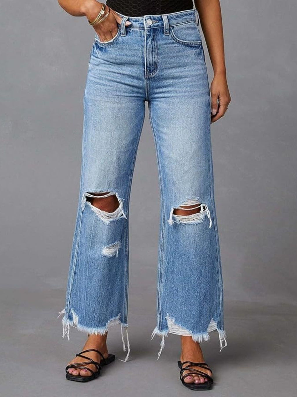 Light blue flare jeans with raw frayed hem and large knee cutouts, front