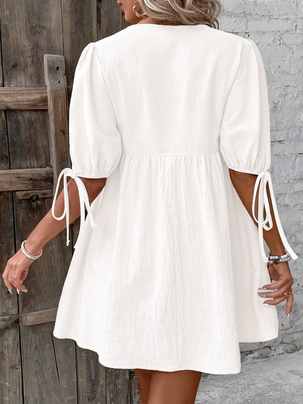 White mini dress from back view, puff sleeves with tie straps