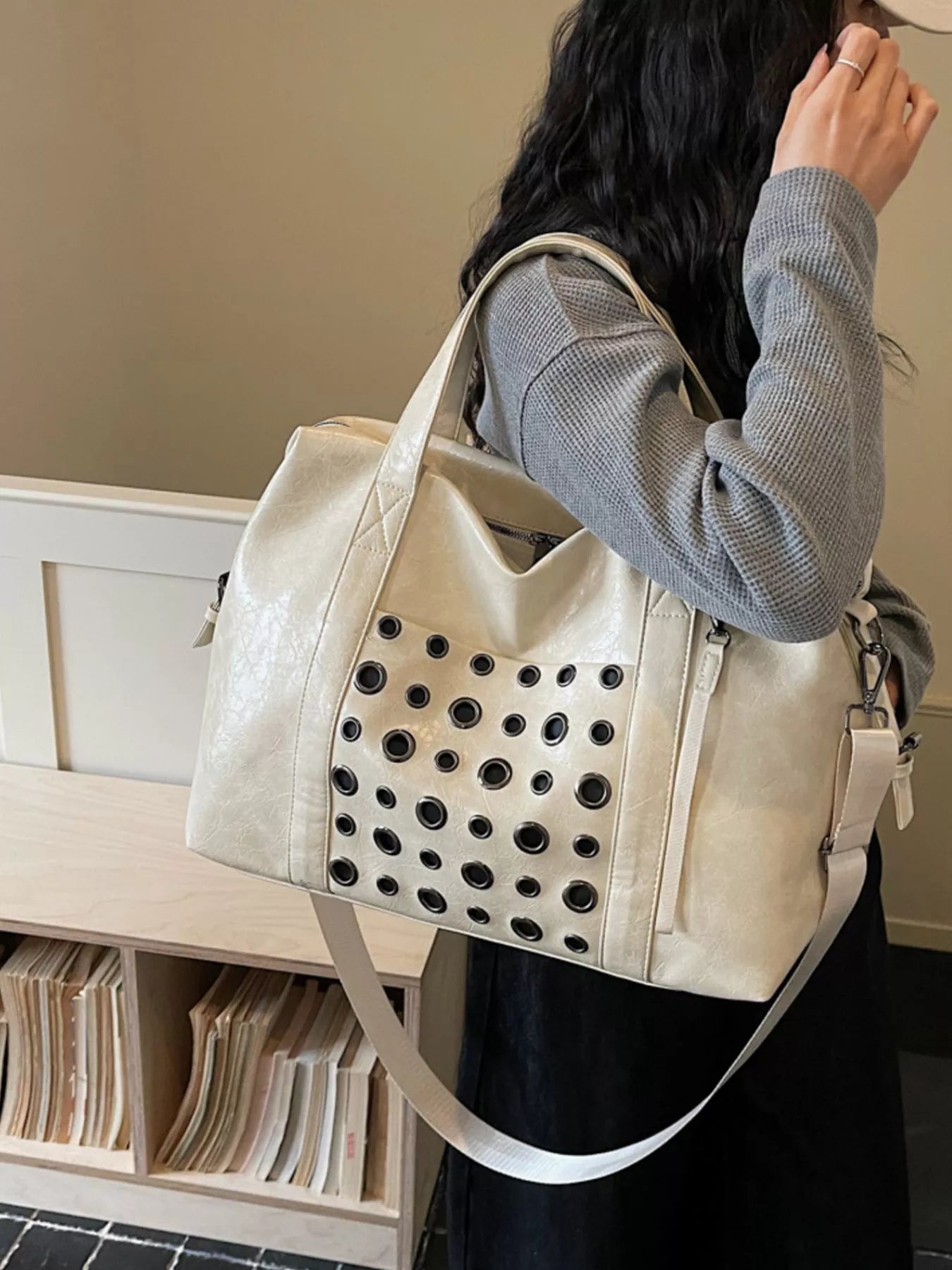 Ivory eyelet crossbody travel bag, wide strap and perforated front pocket detail