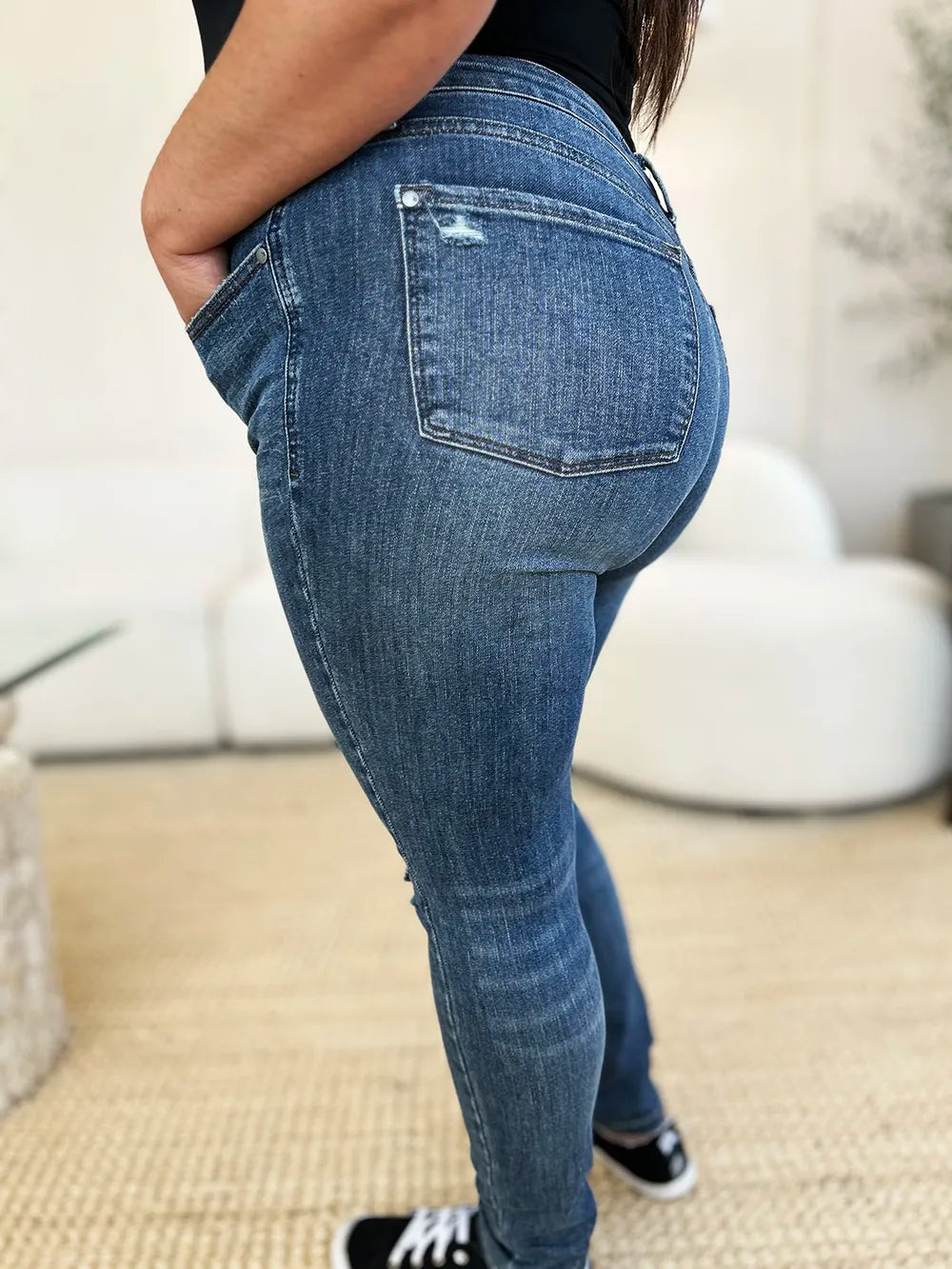 Dark blue slim jeans, side/back view; worn-in wash and ripped knee