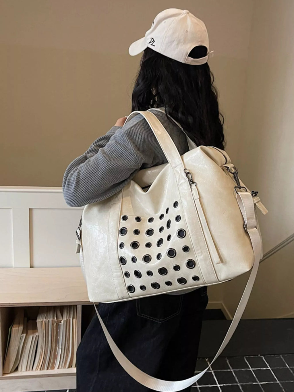 Ivory eyelet crossbody travel bag with perforated front panel and adjustable shoulder strap
