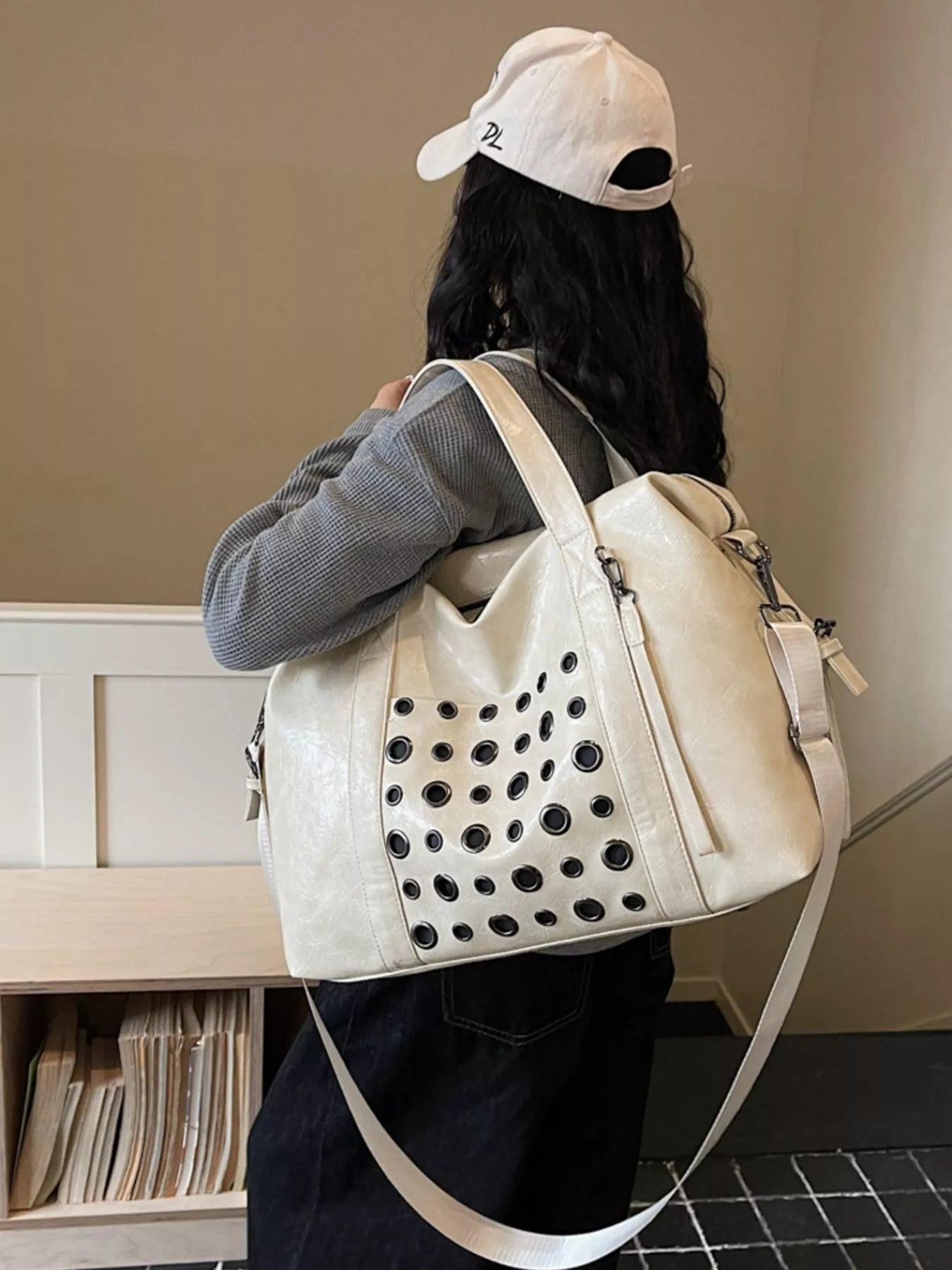 Ivory eyelet crossbody travel bag with perforated front panel and adjustable shoulder strap