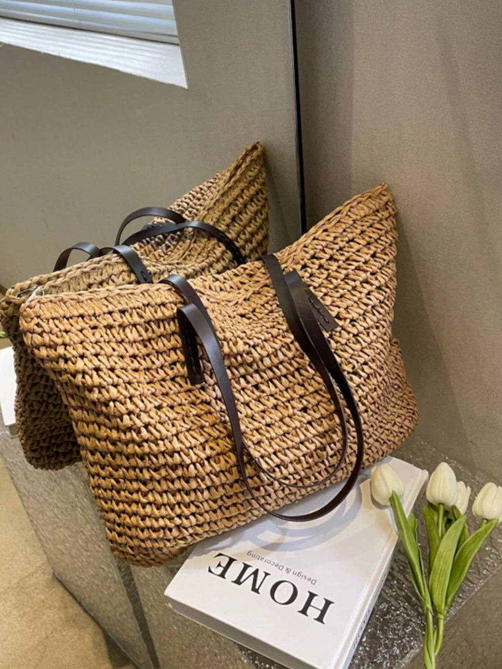Woven straw shoulder bag with black straps, textured weave basket tote in medium warm brown
