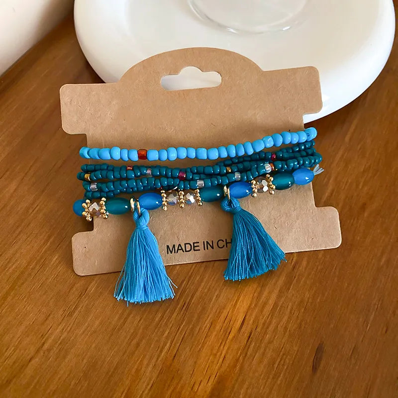 Blue beaded tassel bracelet with two tassels and gold-tone charm accents