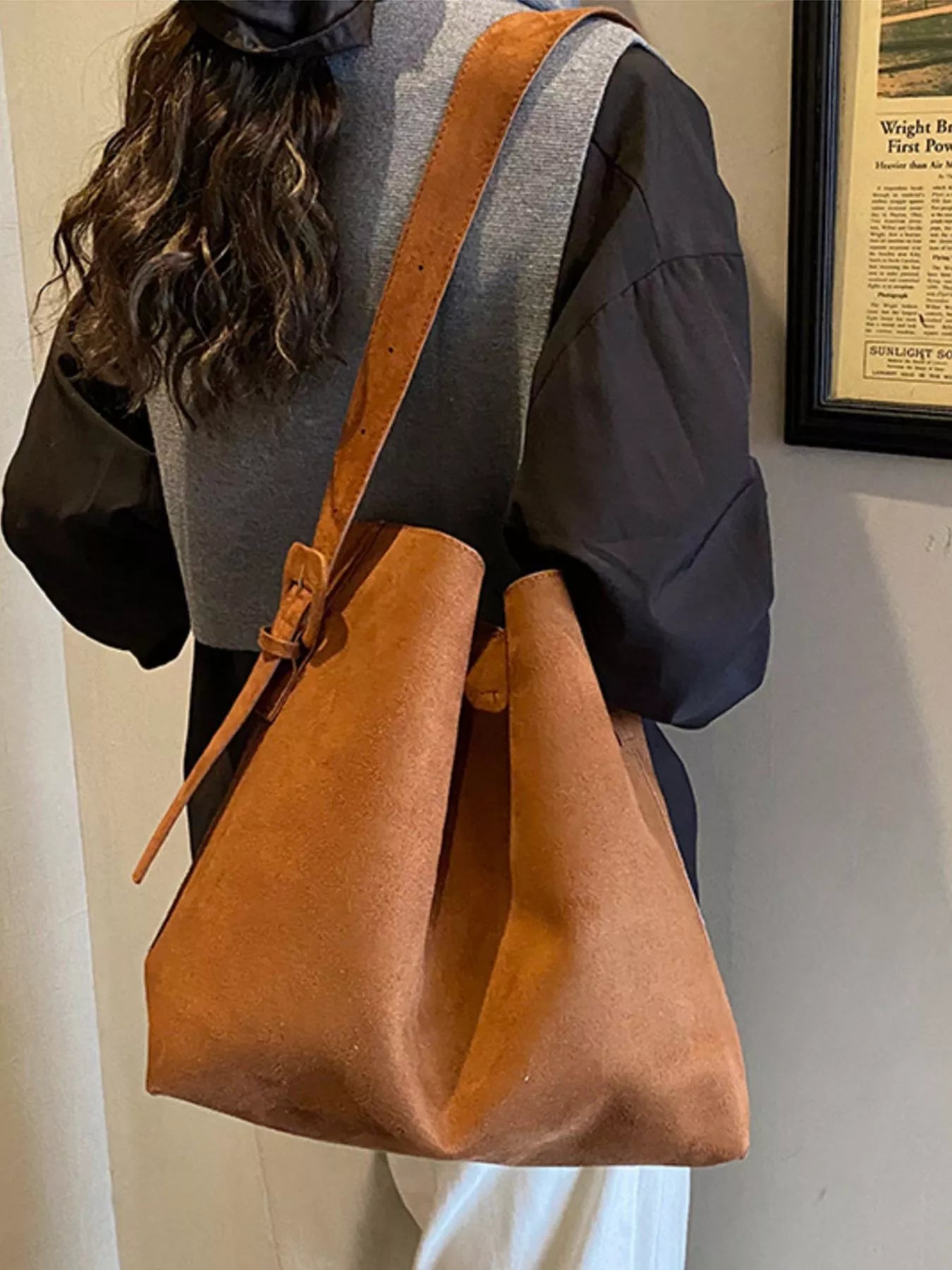 Brown suede tote bag with adjustable strap and hanging tassel tie detail