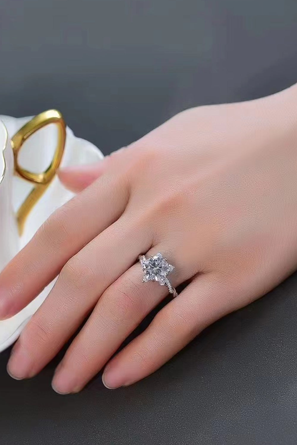 Moissanite twisted ring on hand with small round stones and prong-set center, silver