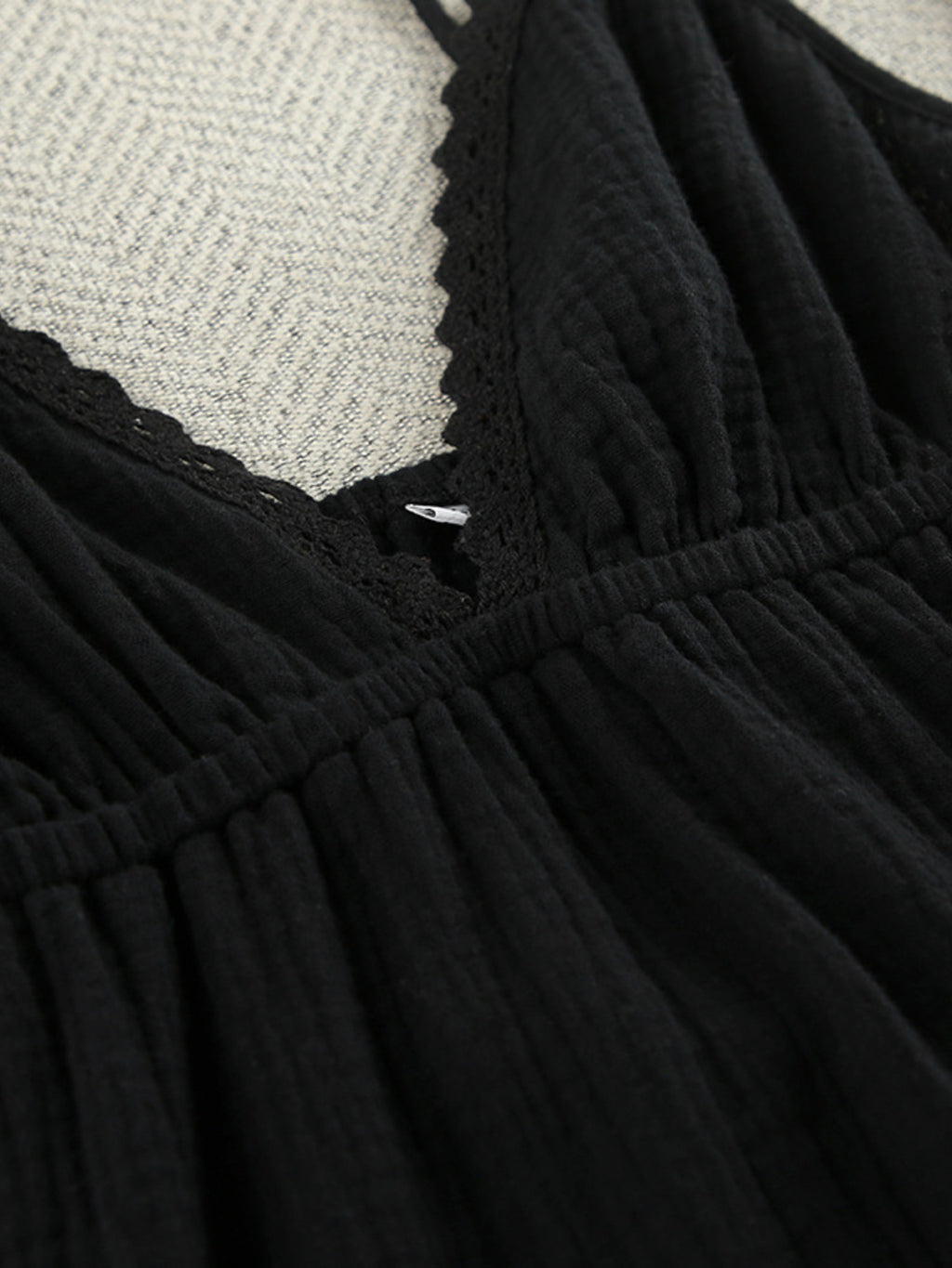 Black V-neck tiered mini dress close-up: lace trim and smocked waist