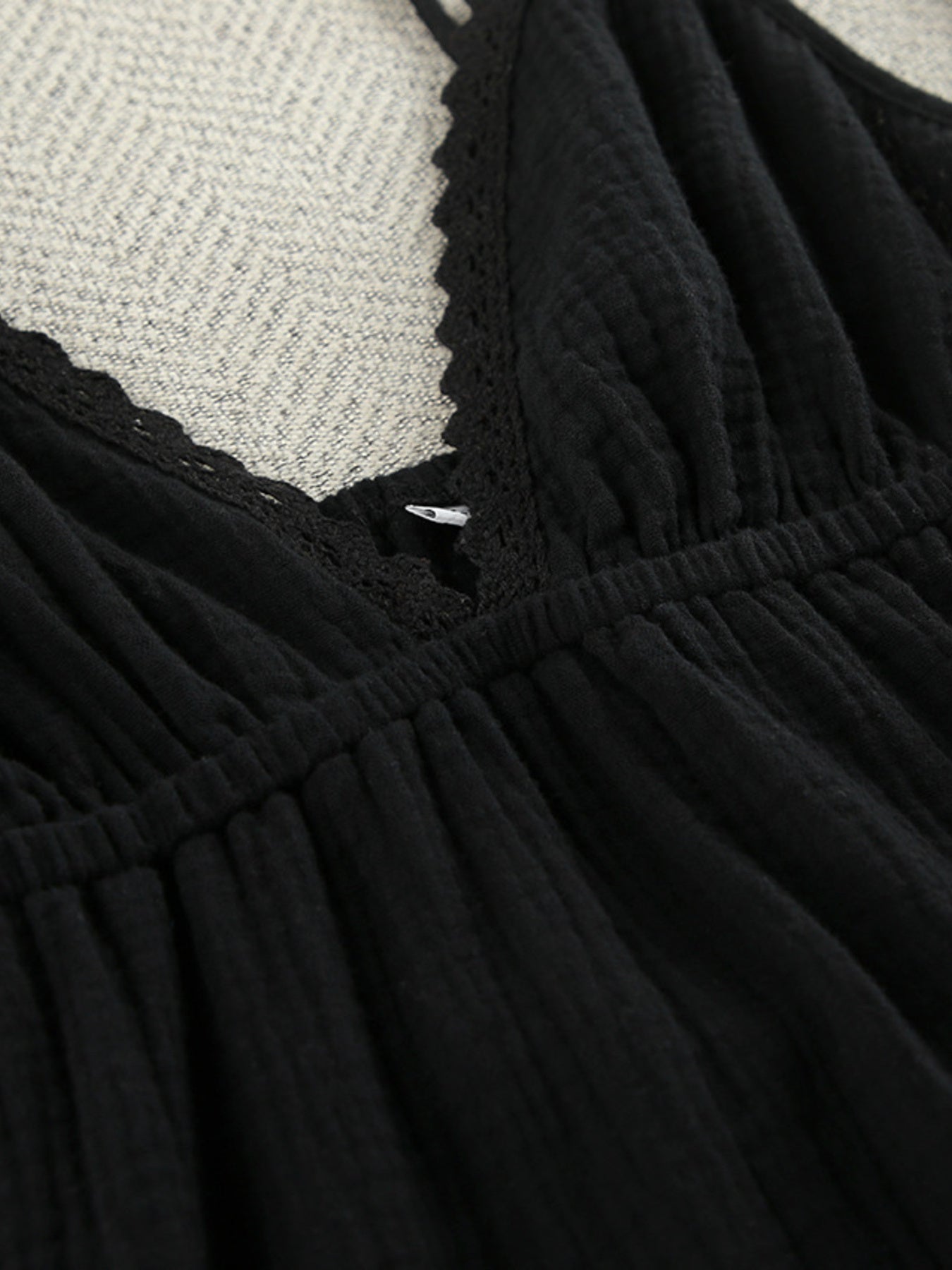 Black V-neck tiered mini dress close-up: lace trim and smocked waist