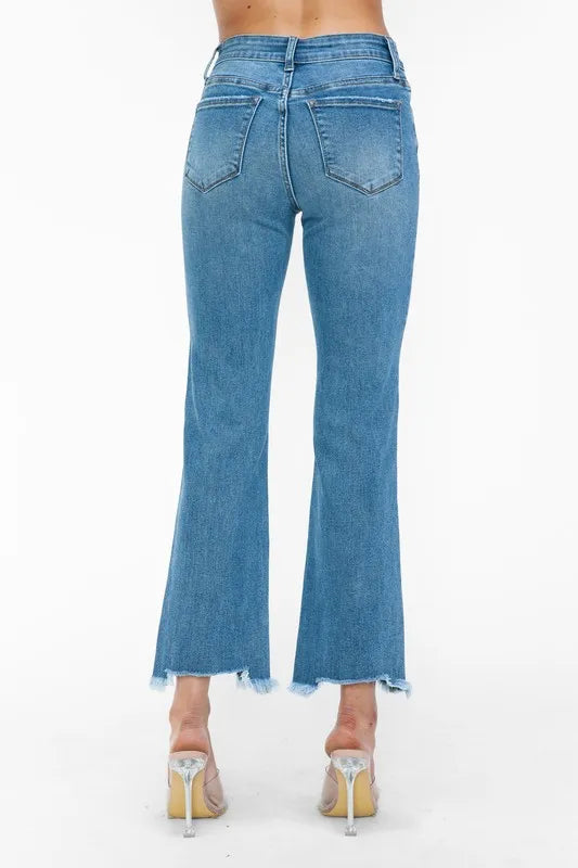 Back close-up of medium-wash mid-rise jeans with raw frayed hem and belt-loop details