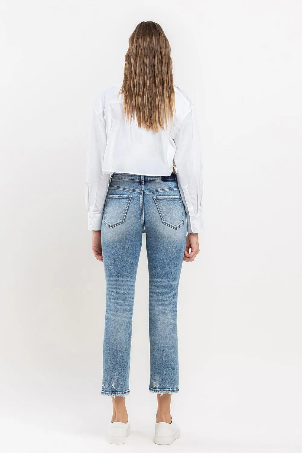 Medium wash high-rise slim straight jeans, back view; back pockets with frayed ankle hem