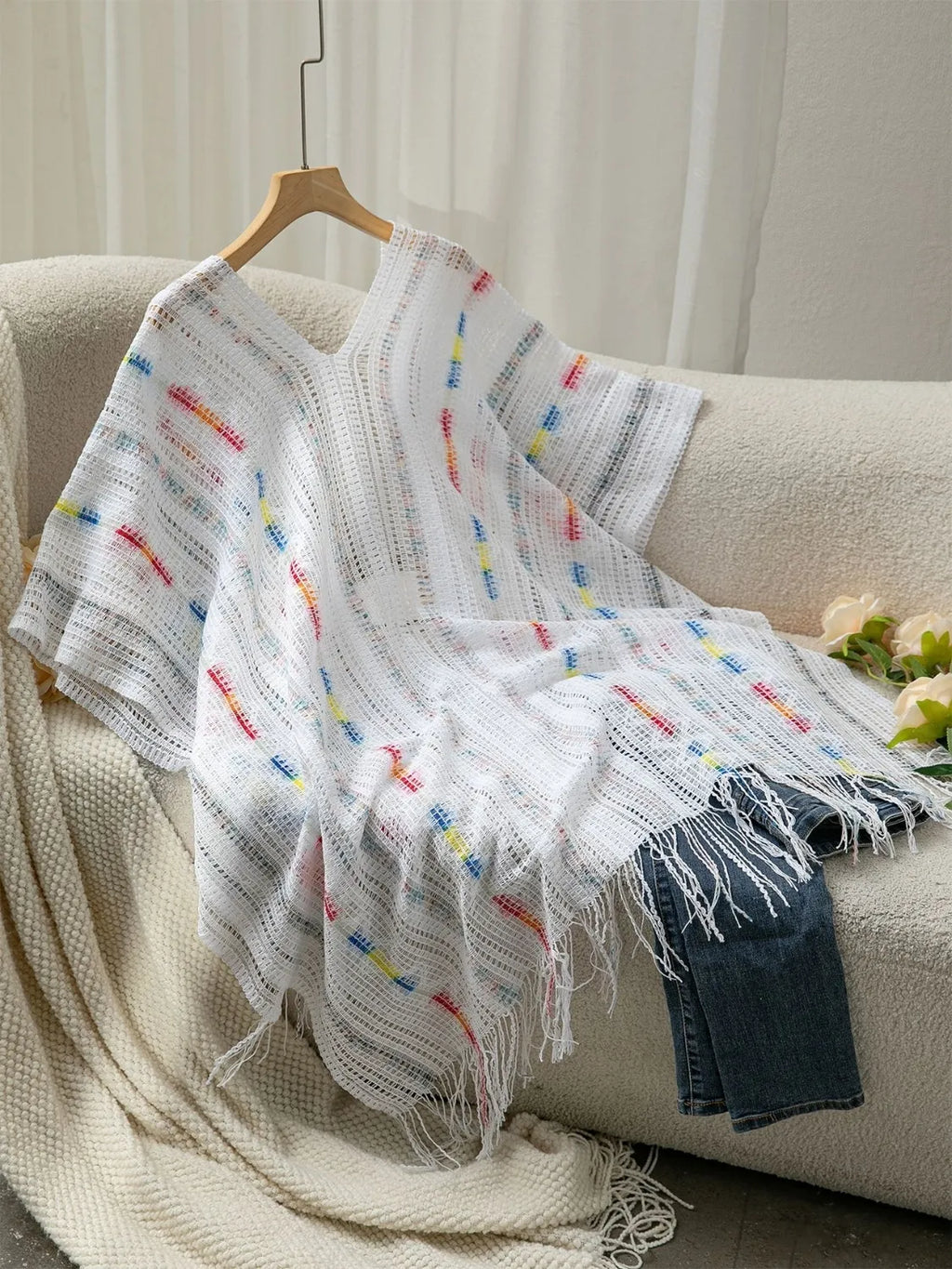 White open-front knit cape with colorful stitched dots and long fringe edges
