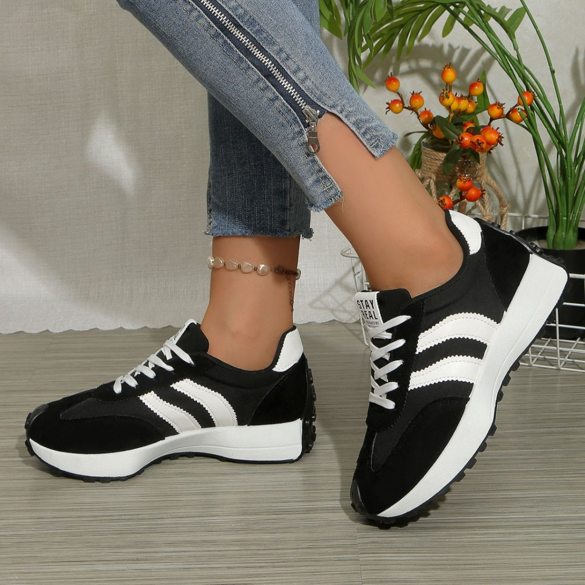 Black and white lace-up sneakers with round toe, white stripe accents, cushioned sole