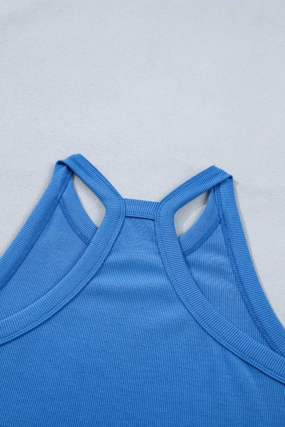 Blue sleeveless cropped top with square high neck and open shoulder cutouts