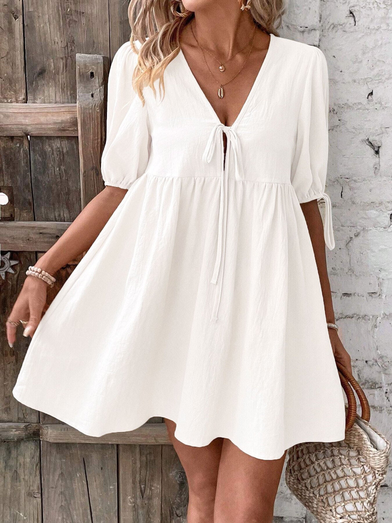 White tie-front mini dress with V-neck, puff sleeves, and flowing gathered skirt