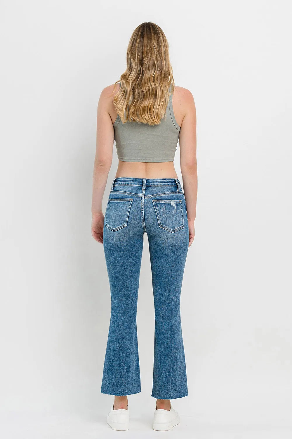 Medium-blue mid-rise flare jeans from back view with rear pockets and distressed wash