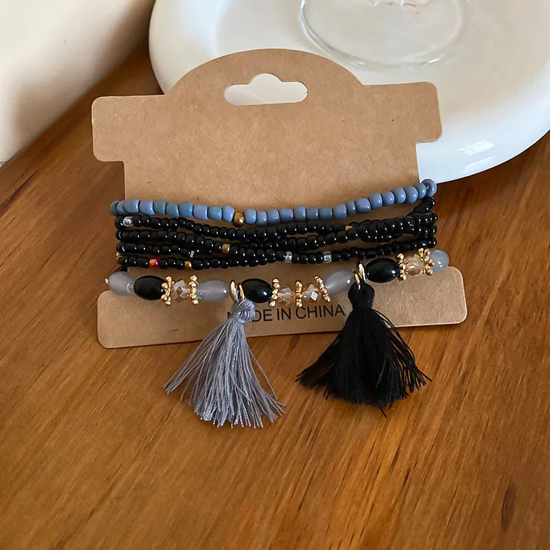Royal blue and black bead tassel bracelet with two tassels and gold-tone charms