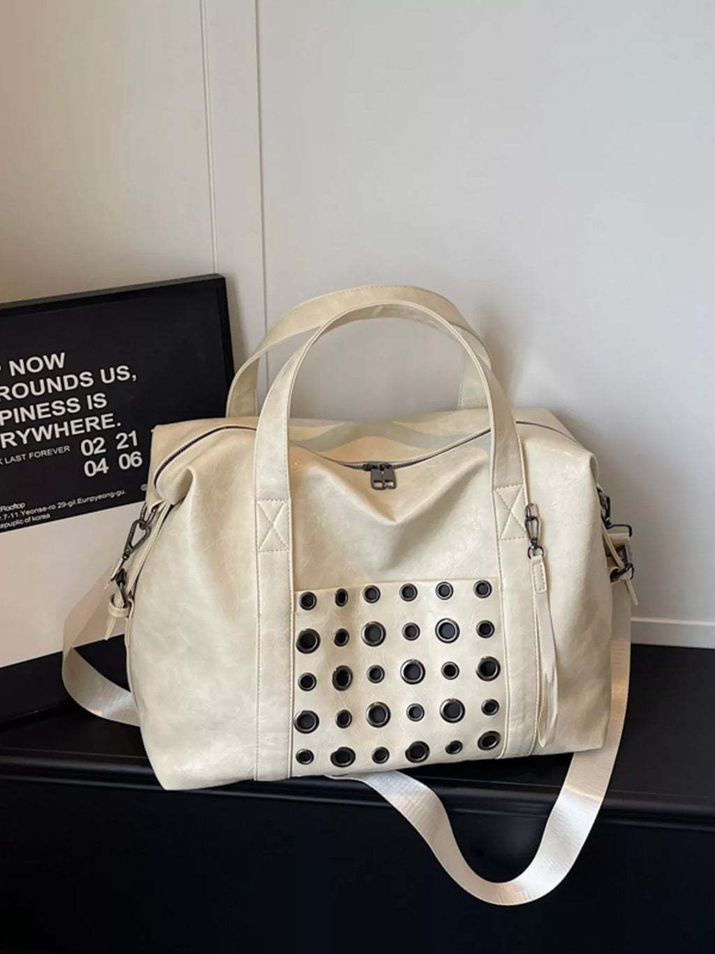 Ivory eyelet embellished crossbody travel bag with top handles and perforated front pocket