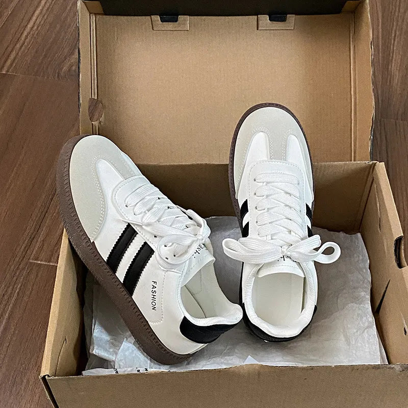 White lace-up sneakers with side stripes and round toe, dark heel tab