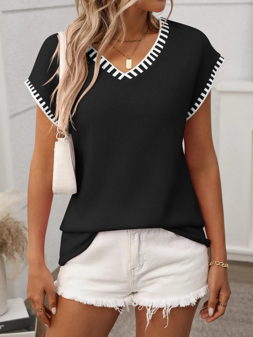 Black v-neck knit top with white contrast trim and short sleeves