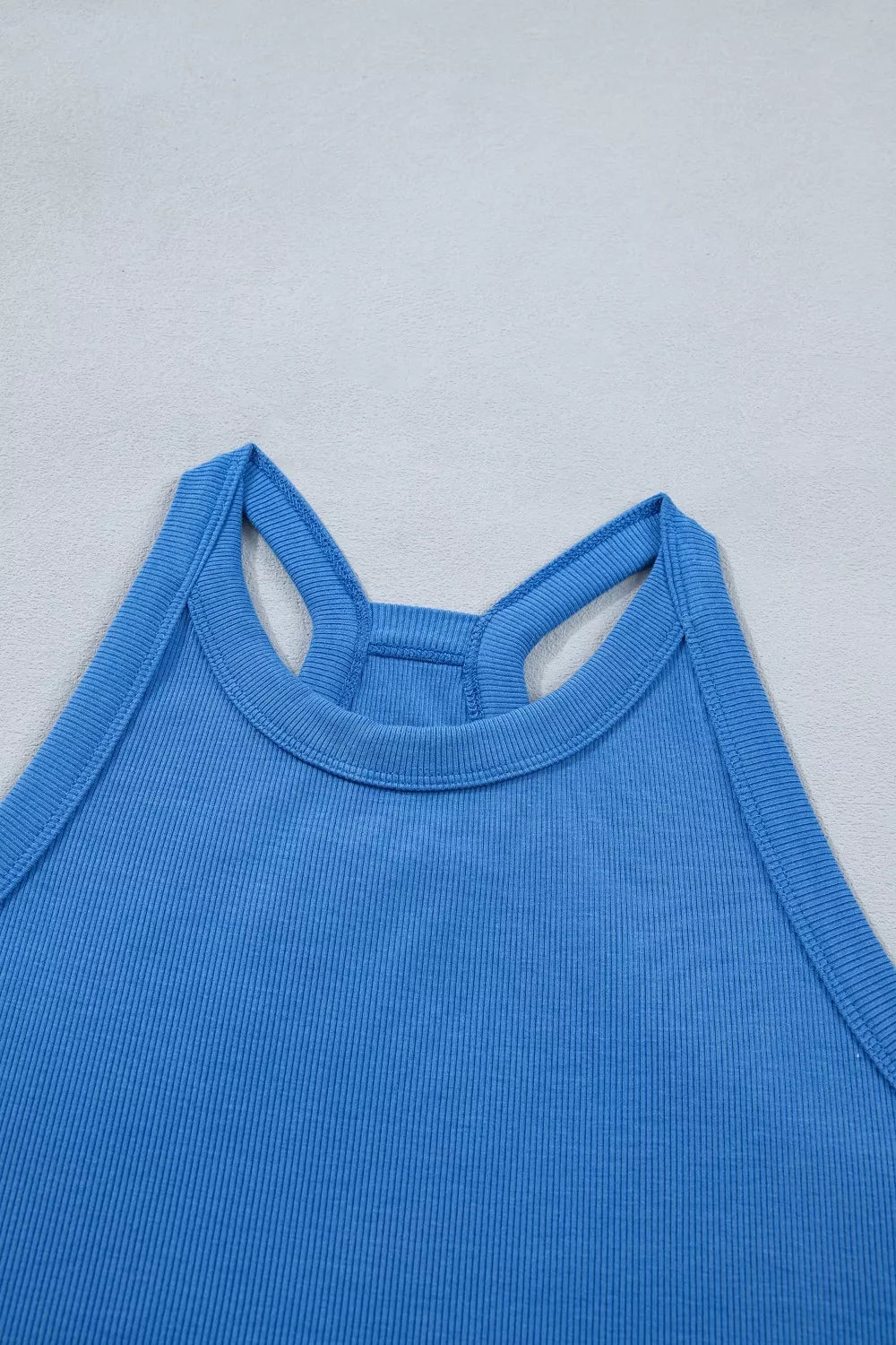 Blue sleeveless cropped top neckline with wide shoulder cutouts and ribbed knit