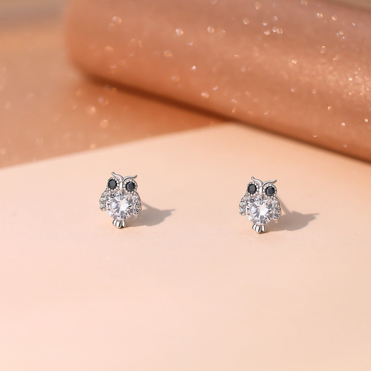 Silver owl stud earrings with round crystal body and black eyes, side-by-side view