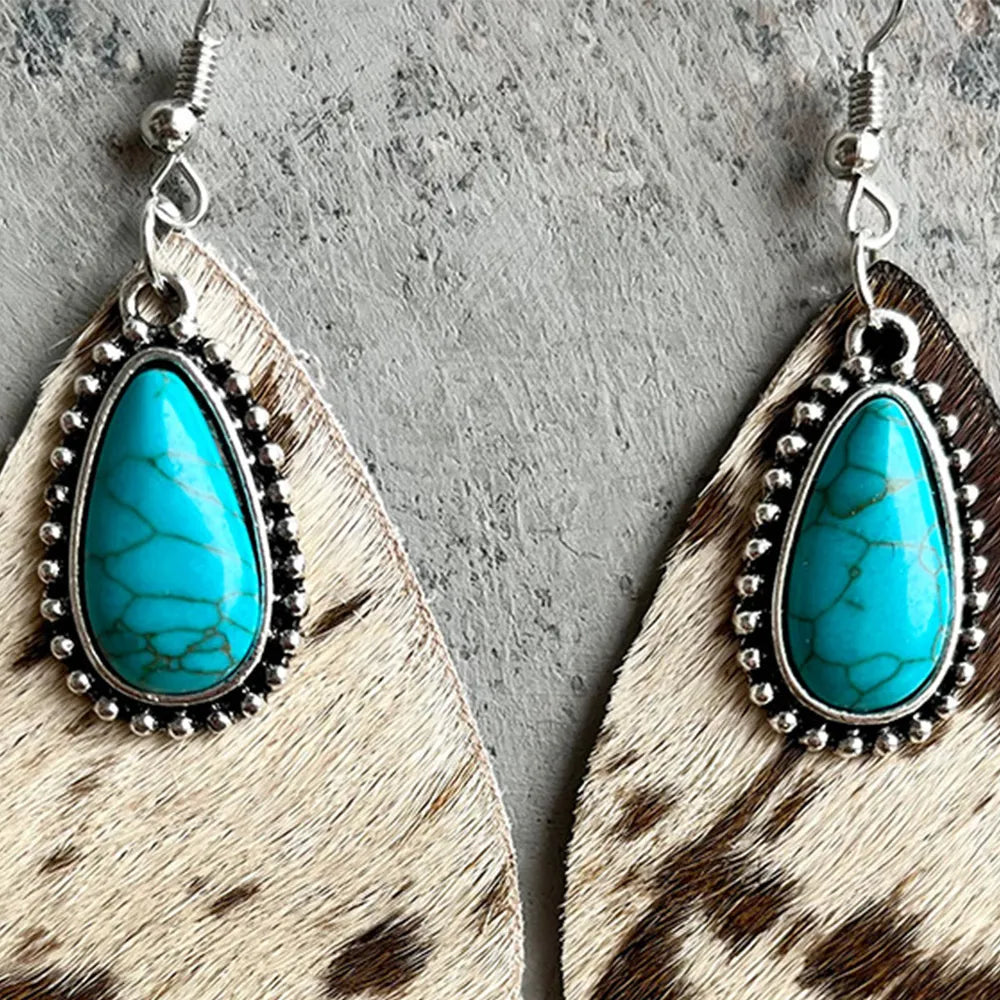 Pair of turquoise teardrop earrings with cow print texture and silver hook backs