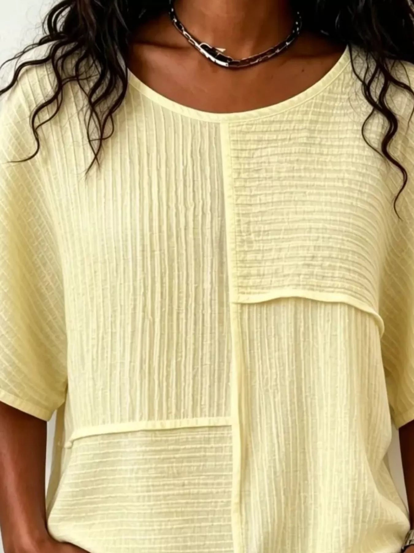 Light yellow textured round-neck half-sleeve blouse close-up of seam panel detail