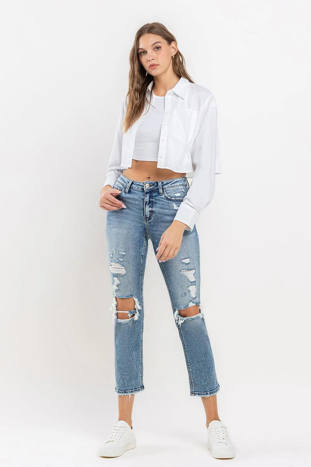 Medium wash high-rise slim straight jeans with button closure and distressed knee rips