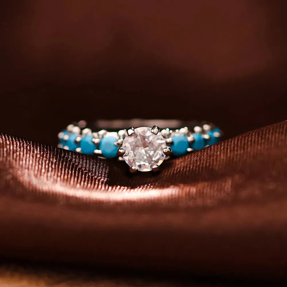 Close-up: turquoise inlay ring with round center zircon and silver prongs